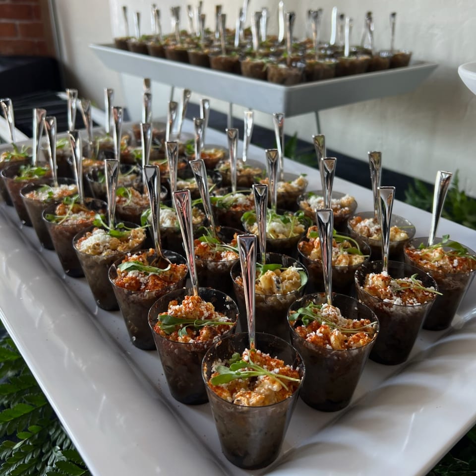 Numerous small cups of Martiniz Fresko Kitchen's brunch appetizers with spoons on a tiered serving tray.