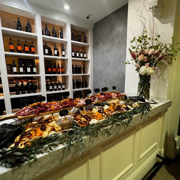 Martiniz Fresko Kitchen's brunch spread with charcuterie, crackers, dried fruit, and wine bottles on shelves.