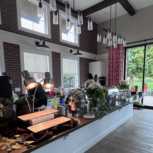 Martiniz Fresko Kitchen's brunch buffet with chafing dishes, white flowers, and brick walls.
