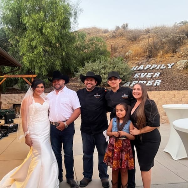 Family and Martiniz Fresko Kitchen staff posing outdoors with a "Happily Ever After" sign.