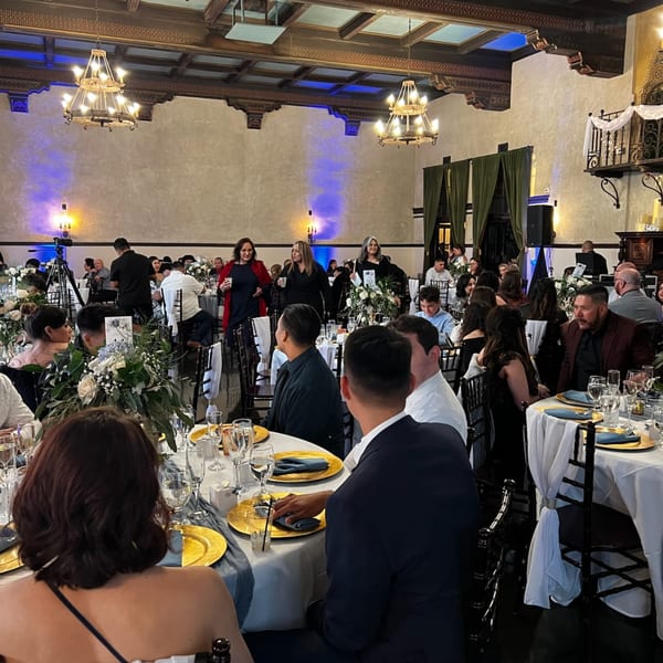 Guests seated at elegantly set tables with floral centerpieces under chandeliers at Martiniz Fresko Kitchen.