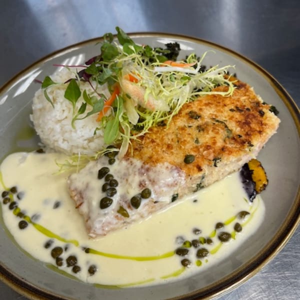 Crispy salmon with caper cream sauce, white rice, and fresh greens on a plate.