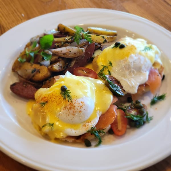 Martiniz Fresko Kitchen's Eggs Benedict with smoked salmon, roasted potatoes, and cherry tomatoes.